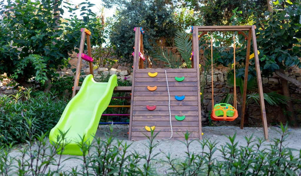 ogrodowy, drewniany plac zabaw dla dzieci ze zjeżdżalnią, ścianka wspinaczkową i huśtawką